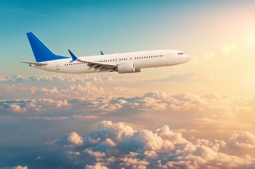 Commercial airplane flying above cloudscape in dramatic toned sunset light